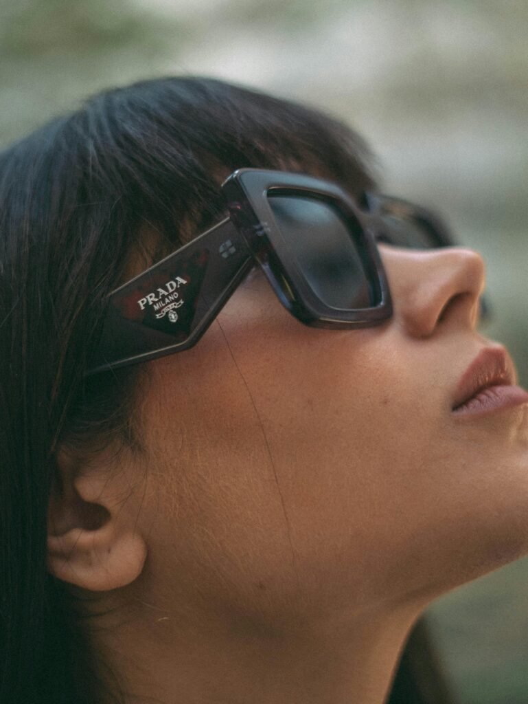 Side view close-up of a woman wearing fashionable Prada sunglasses, emphasizing style and elegance.