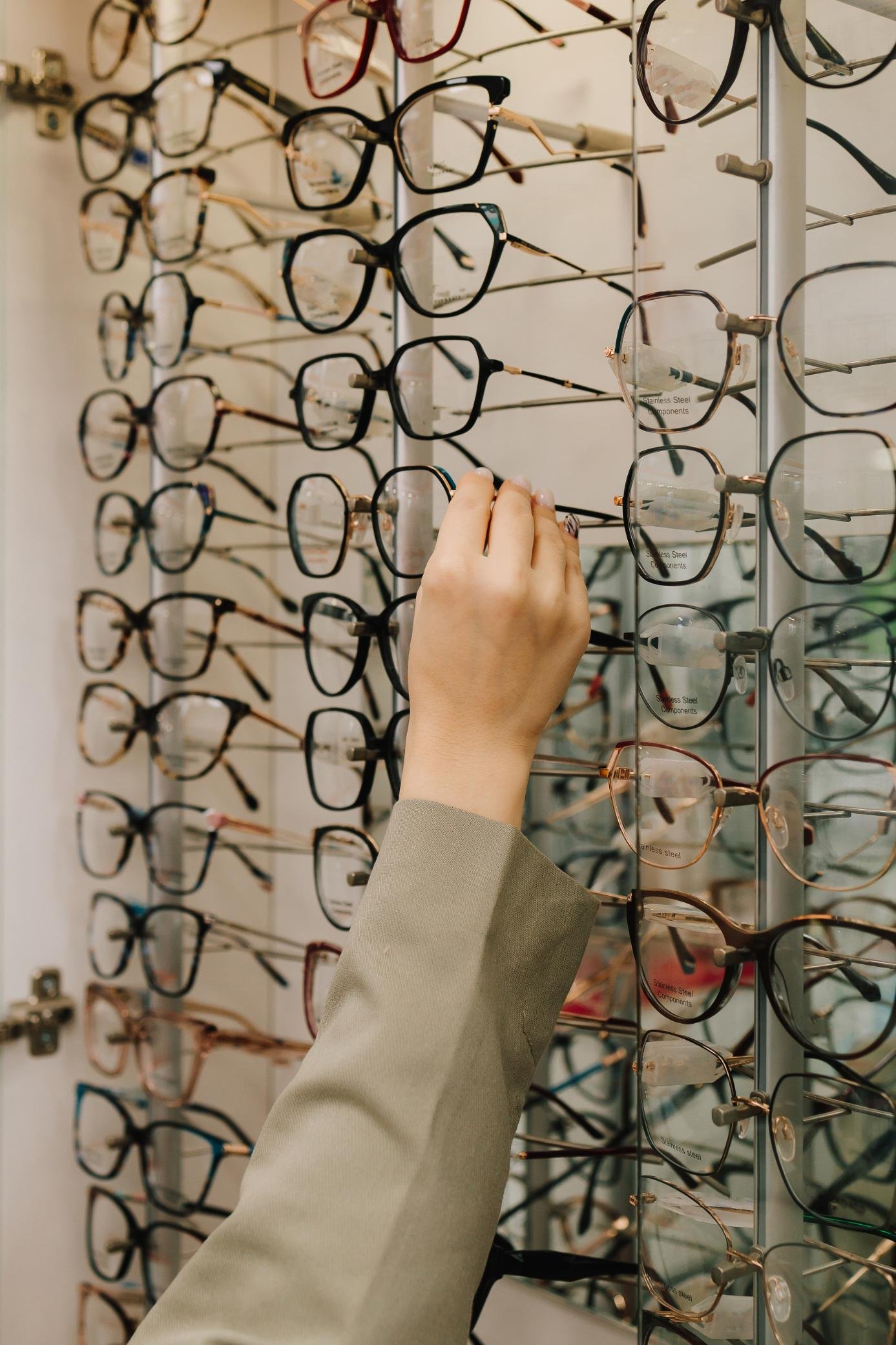 stand-eyeglasses-with-different-frames-optical-store-customer-chooses-eyeglasses-with-clear-lenses-from-shelf-eyesight-correction